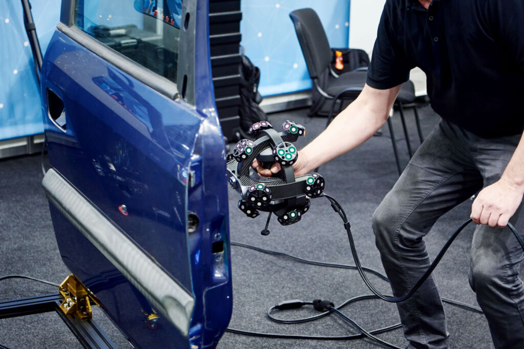 Man with tracking 3D scanner of optical scanning system and cars door