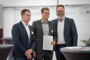 Bei der Übergabe des Förderbescheids für den VisiConsult-Neubau in Stockelsdorf (v.l.n.r.): Finn Schulenburg und Lennart Schulenburg (beide Gesellschafter sowie Geschäftsführer), Claus Ruhe Madsen (Minister für Wirtschaft, Verkehr, Arbeit, Technologie und Tourismus des Landes Schleswig-Holstein)