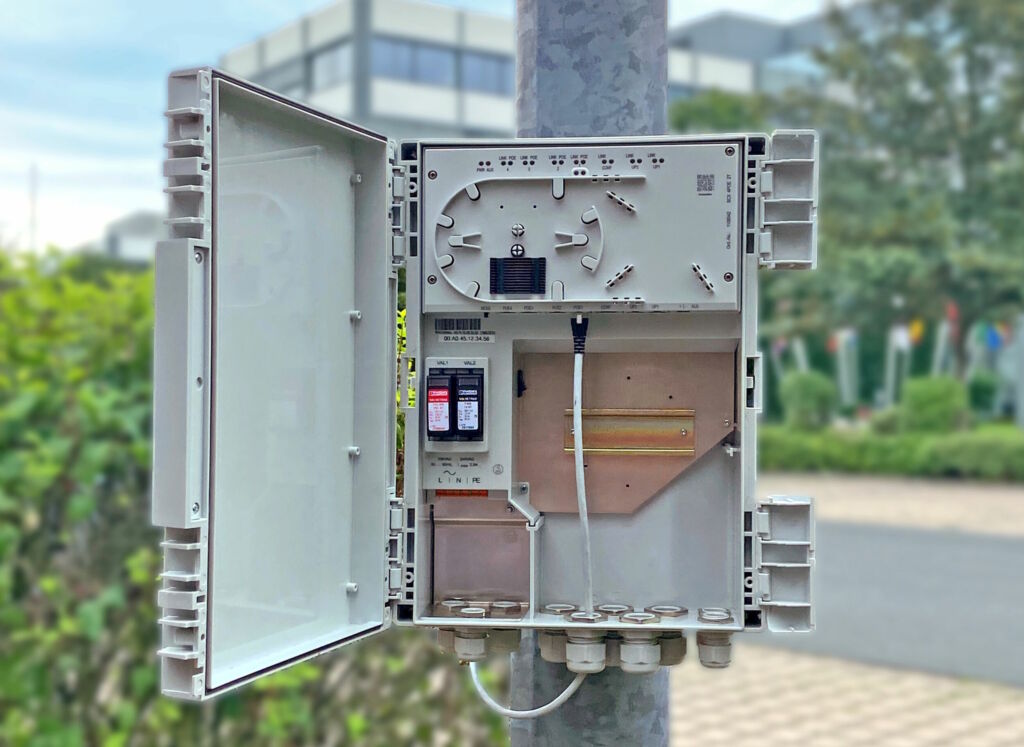 Offene Smart Camera Box an einem Mast vor einem Gebäude.