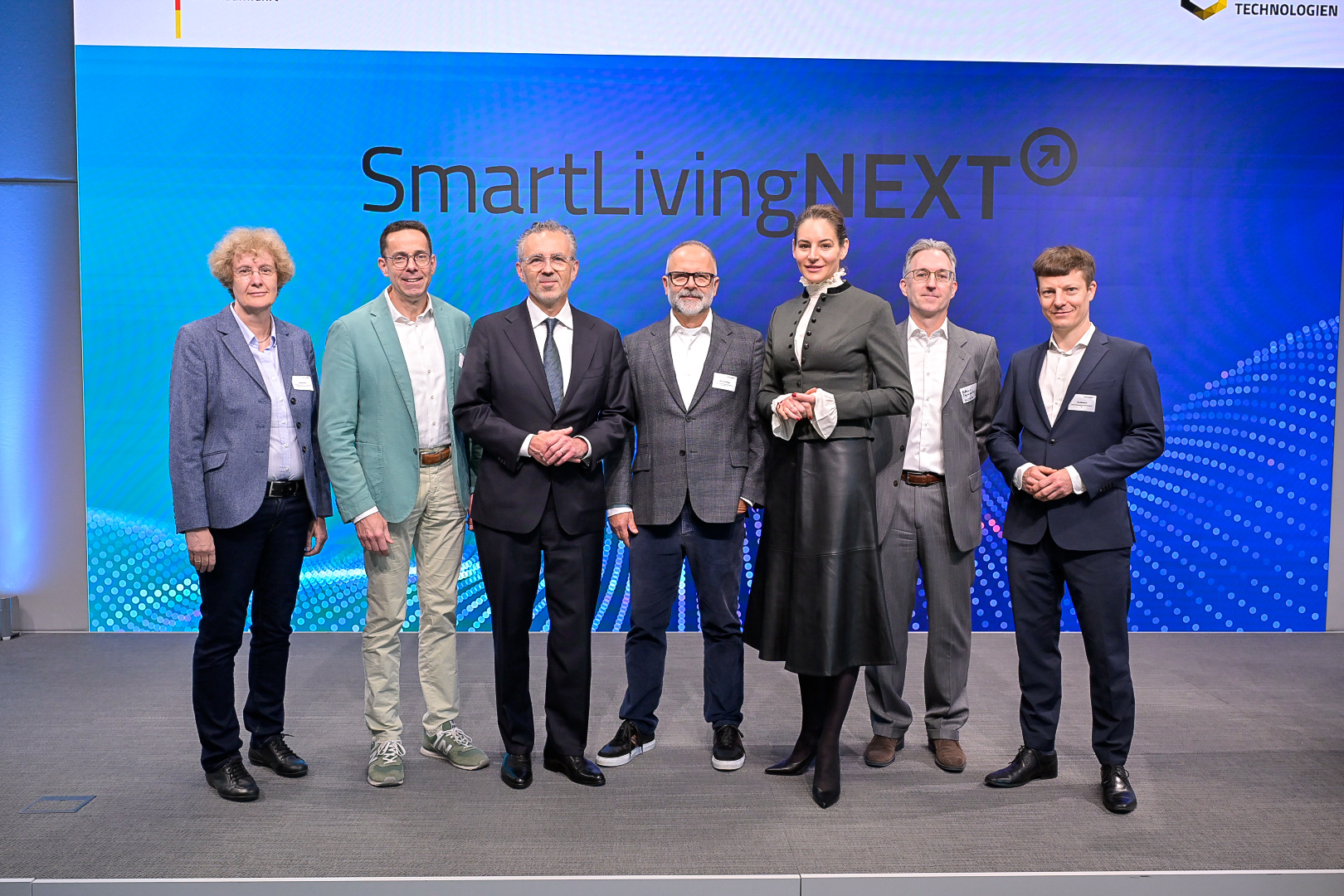 Diskutierten auf der SmartLivingNEXT-Konferenz im Forum Digitale Technologien in Berlin über den Start in den Realbetrieb: Ute Bernhardt, Leiterin des Referats Künstliche Intelligenz im Bundesministerium für Forschung, Technologie und Raumfahrt (BMFTR), Wolfgang Weber, Vorsitzender der ZVEI-Geschäftsführung, Thomas Jarzombek, Parlamentarische Staatssekretär beim Bundesminister für Digitales und Staatsmodernisierung, Michael Schidlack, Principal Researcher bei der Forschungsvereinigung Elektrotechnik beim ZVEI e. V. und Projektleitung des SmartLivingNEXT Leitprojekts, Dr. Alexandra-Gwyn Paetz, Abteilungsleiterin Technologische Souveränität & Innovation, Bundesministerium für Forschung, Technologie und Raumfahrt (BMFTR), Matthias Szymansky, Kompetenzzentrumsleiter Analytics & AI bei Materna Information & Communications SE, Filip Milojkovic, Teamleiter Data Management & AI bei Materna Information & Communications SE (v. l.).