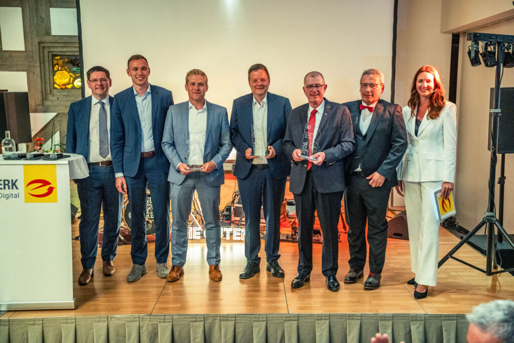 Die Gewinner der E-Markenpartner-Preise 2026: Felix und David Braun (2. u. 3. v. l.), Andreas Bettermann (4. v. l.) und Burkard Kaiser (3. v. r.), hier mit ZVEH-Präsident Stefan Ehinger (l.) und Olaf von Müller (2. v. r.), ZVEH-Vizepräsident und Vorsitzender der ArGe Medien im ZVEH, und Moderatorin Anja Lange (r.).