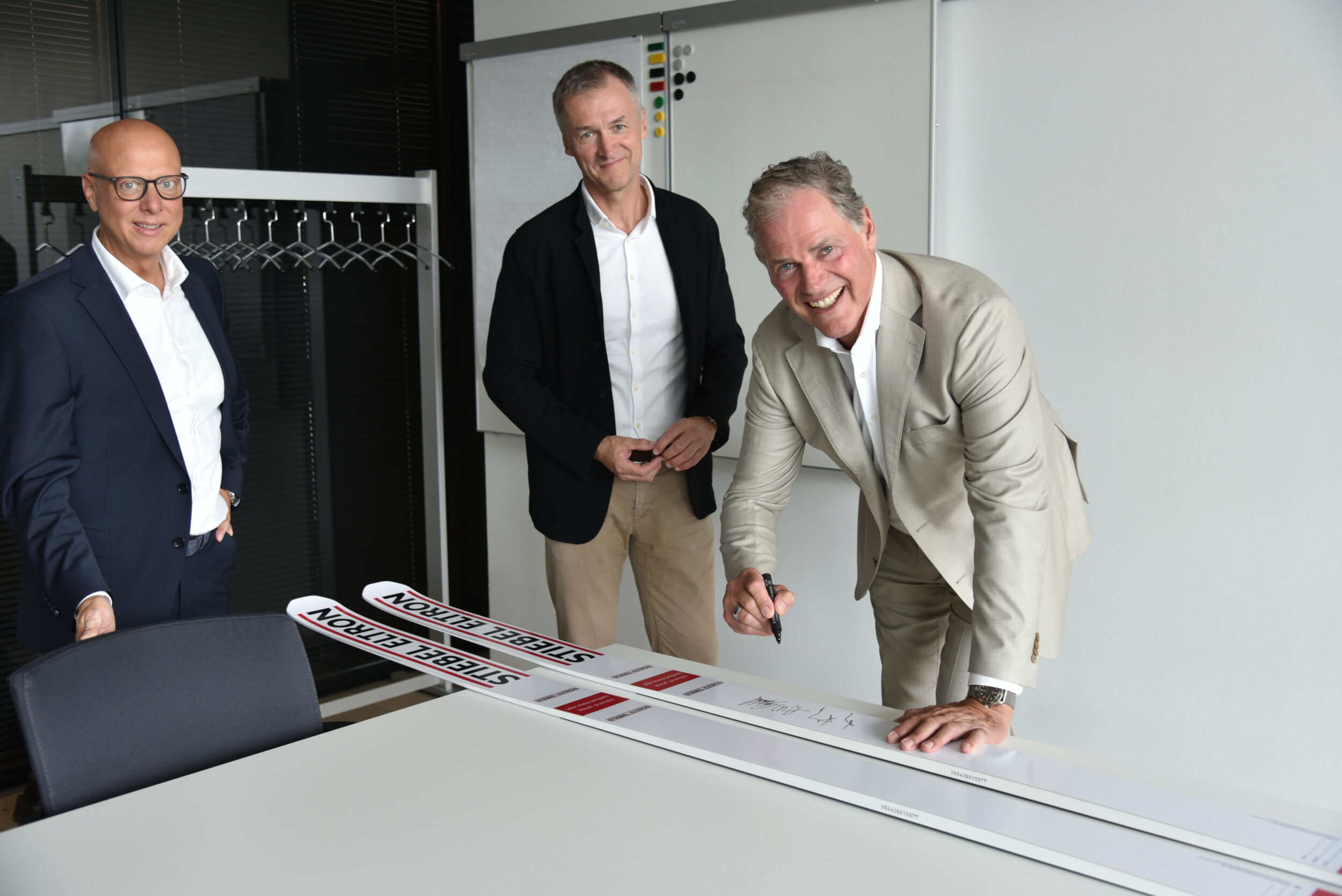 Die Zusammenarbeit zwischen Fischer Sports und Stiebel Eltron wurde stilecht auch per Unterschrift von Heinz-Werner Schmidt(rechts) und Franz Föttinger auf echten Sprungski mit Stiebel Eltron-Branding besiegelt. Links Claus Kroll-Schlüter, Leiter MarketingCommunication von Stiebel Eltron.