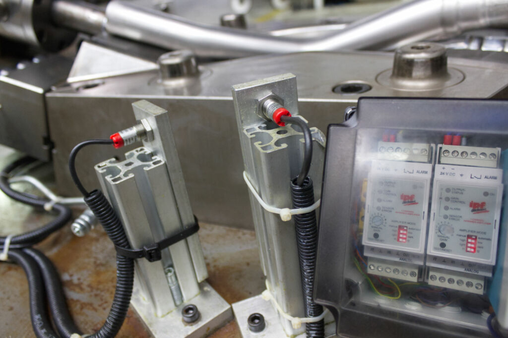 Zwei Hochleistungslichtschranken, die jeweils mit einem Einkanalverstärker (rechts) verbunden sind. Sender und Empfänger werden direkt an das Unterwerkzeug montiert und als steckbare Systeme an die an den Pressen installierten Einkanalverstärker angeschlo