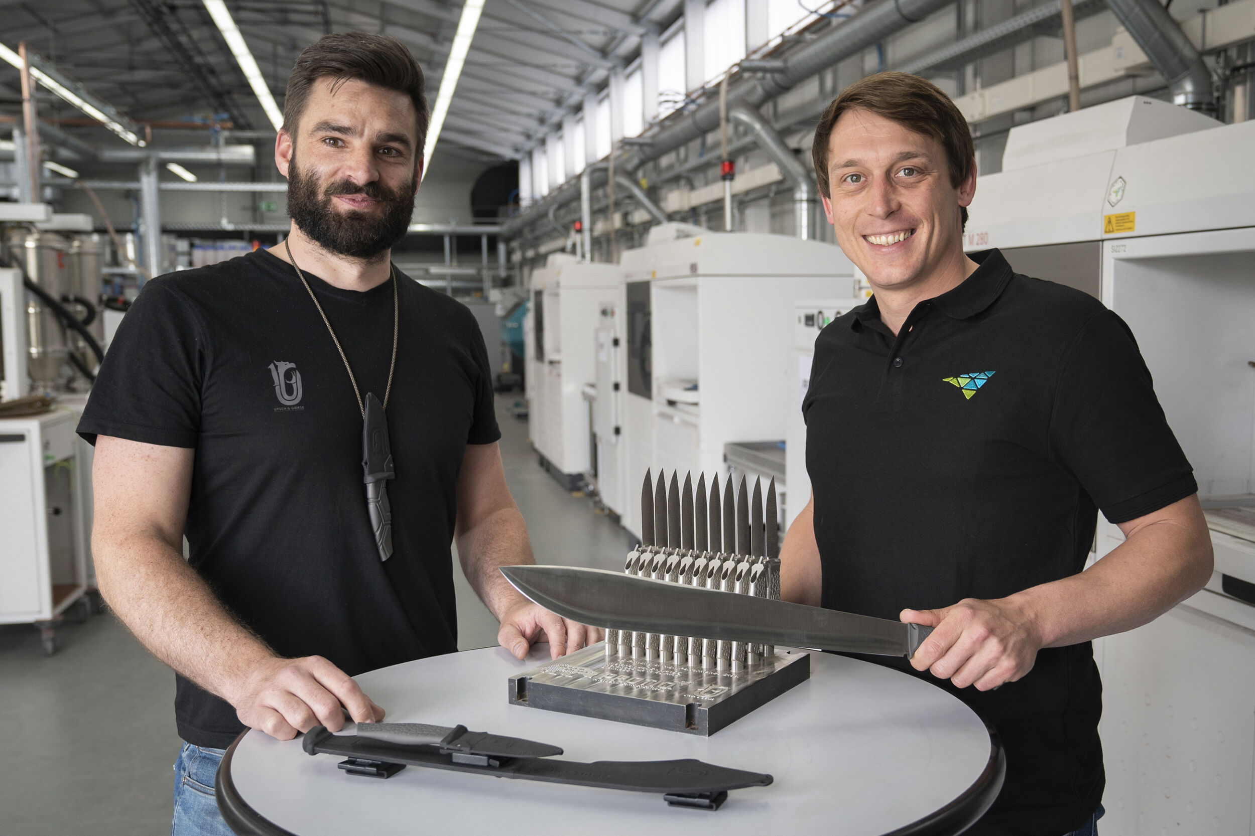 Jan Gierse von UG-Tools (l.) und Johannes Lohn (Protiq) pr&auml;sentieren hochwertige Messer und Klingen der Messermanufaktur. Diese werden mit 3D-gedruckten Griffen aus Titan oder vollst&auml;ndig aus 440C additiv gefertigt.