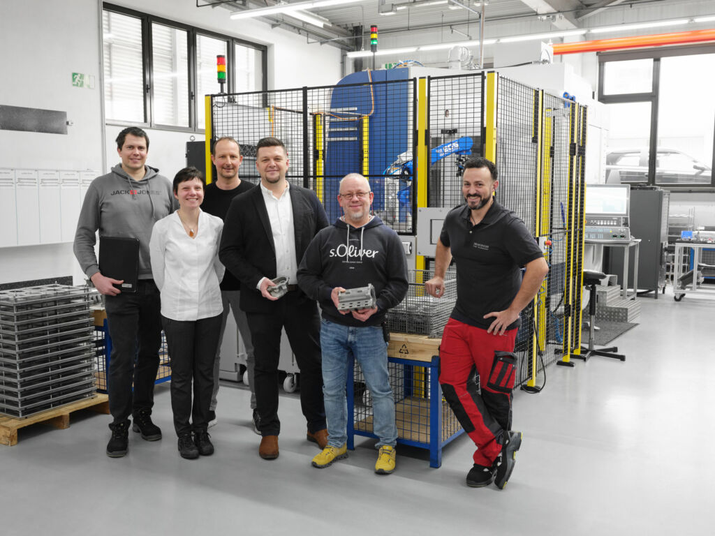 Das hochgesteckte Ziel einer vollautomatisierten mannlosen Fertigung dank ausgezeichneter Zusammenarbeit aller Beteiligten in Rekordzeit erreicht (v.l.): Mario Maier, Sabrina L&ouml;ffler und Tobias King (alle Scherzinger) mit Willi Fast von AMF neben Oliver Hindinger und Fabio Manzanillo (beide Scherzinger). 
