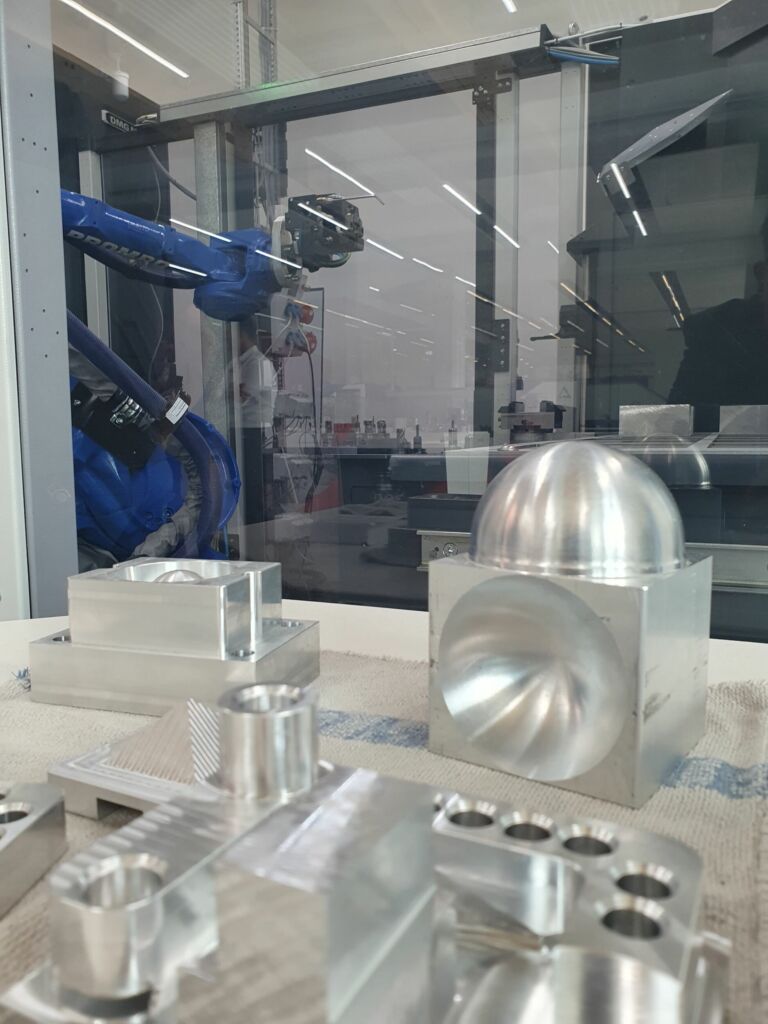 Roboterl&ouml;sung an einer DMG Mori DMV 115 mit dem Modul R-C2 von Gressel f&uuml;r die komplett mannlose 6-Seiten-Bearbeitung von Bauteilen, hier aus Aluminium.