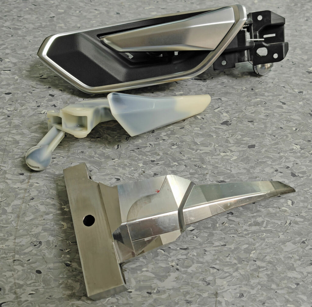 Sicherheitsteil T&uuml;rinnenbet&auml;tigung: Dieses Bauteil darf keinesfalls brechen - oben die fertige Baugruppe, in der Mitte das unbeschichtete Spritzgussteil, unten der bewegliche Kern des entsprechenden Werkzeugs. 