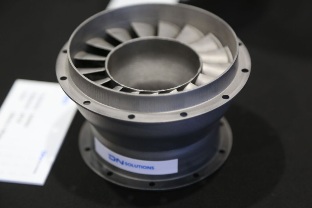 Das Flaggschiff der neuen Sparte Additive Manufacturing ist der 3D-Metalldrucker DLX 450D. Das kleinere Bild zeigt ein komplexes, pr&auml;zises und innovativ gefertigtes Demobauteil.