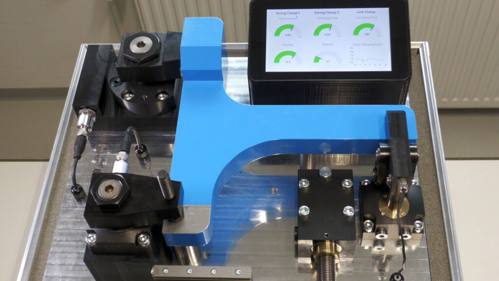 Sensorische Spannvorrichtung mit verschiedenen Spannelementen wie Hebelspanner, Schwenkspanner und Bohrungsspanner, ausgestattet mit umfangreicher Sensorik f&uuml;r Industrie 4.0-Applikationen. 