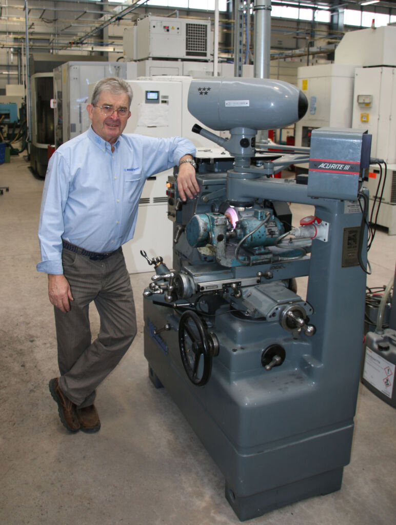 Unternehmensgründer John Inglis mit der ersten Maschine, die er 1979 anschaffte - noch lange bevor die erste Vollmer Maschine Einzug in die Produktion hielt.