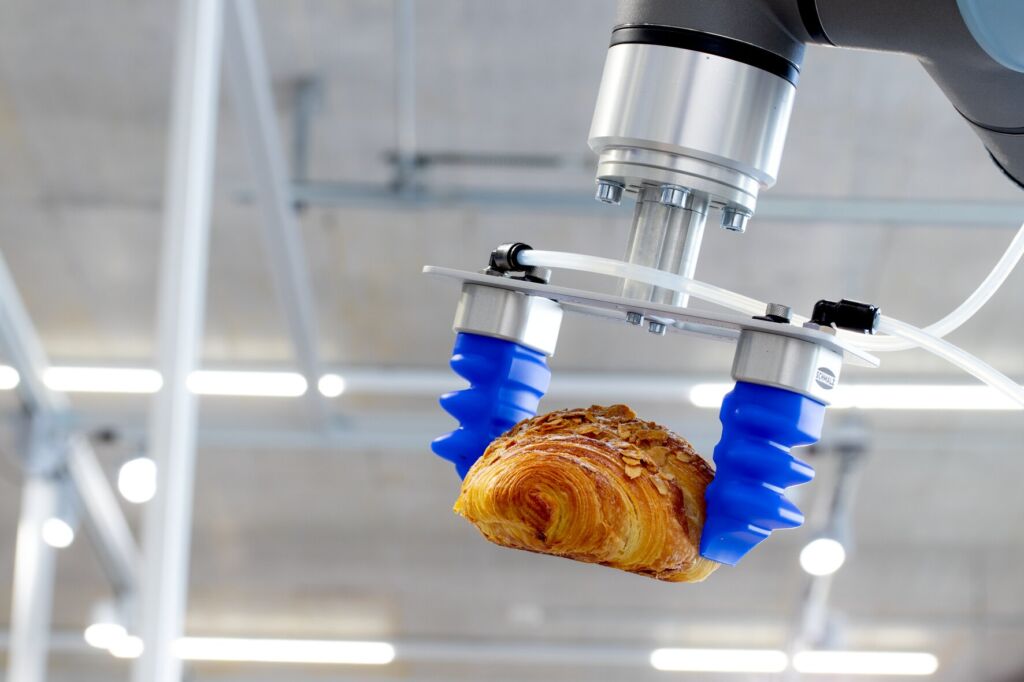 Der Fingergreifer mGrip Basic fasst empfindliche, blättrige Backwaren wie Croissants behutsam und legt sie für die automatisierte Verpackung schonend ab.