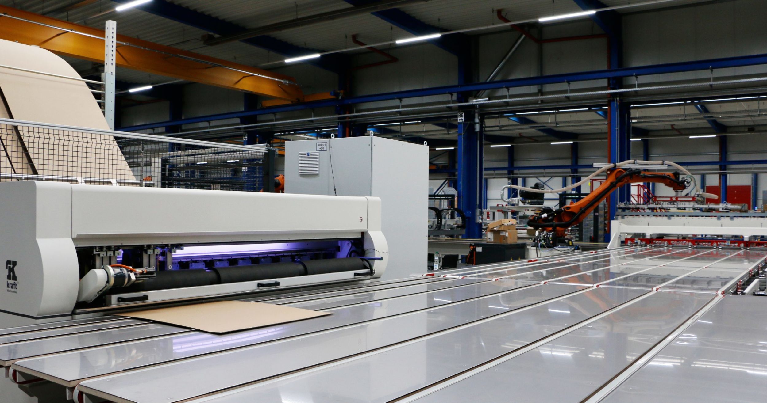 Der Kraft-Kartonschneideautomat VPS100 stellt die passgenauen Kartons für die Werkstücke her. Die Maschine bedient sich vollautomatisch aus dem Rohpappenspeicher und wählt die entsprechende Pappe mit dem geringsten Verschnitt für das Werkstück aus.