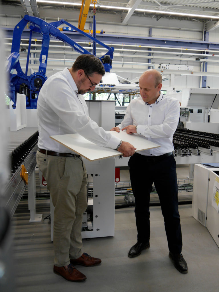 Tech-Talk zur Automatisierung bei Losgröße 1 1 Auf die klassische Art: Die Homag Experten prüfen die Schnittqualität - während für den Homag Treff im Hintergrund schon eine Sawteq B-320 flexTec mit MSQ aufgebaut wird.