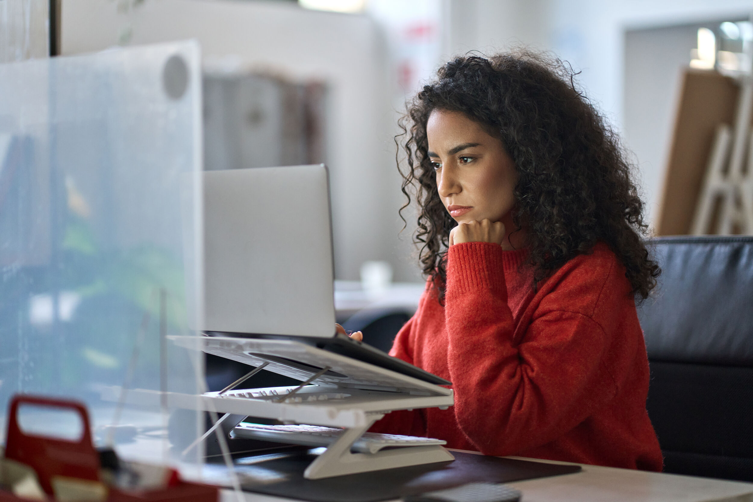 Busy latin female worker working on laptop thinking analyzing online data