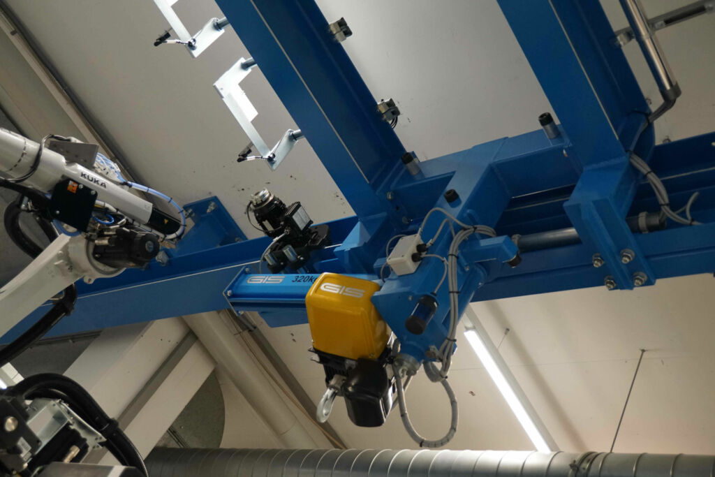 Der Laufkran wird in Längsrichtung verschoben. Hierzu ist der Drehkran eingeschwenkt arretiert und wird zwischen Säule und Handlingroboter bewegt.