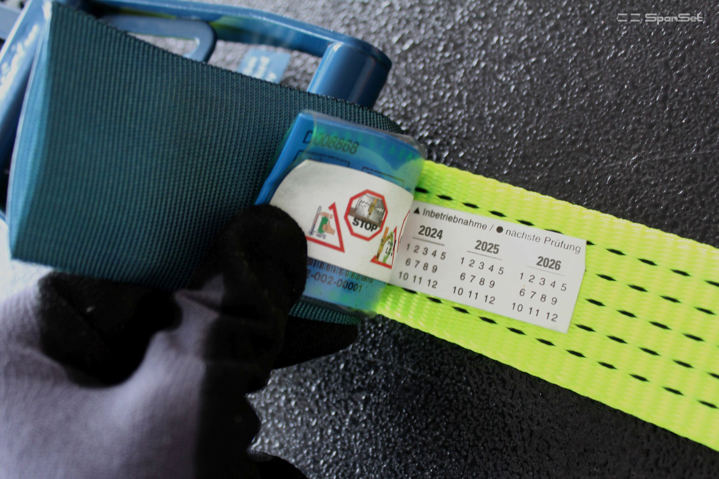 Produktlabel mit Herstelljahr und Rückverfolgbarkeitscode als Barcode und Zahlenfolge (i) für (a) Fest- und (b) Losende. Zurrsystem mit STF-Angabe sind für das Niederzurren geeignet.