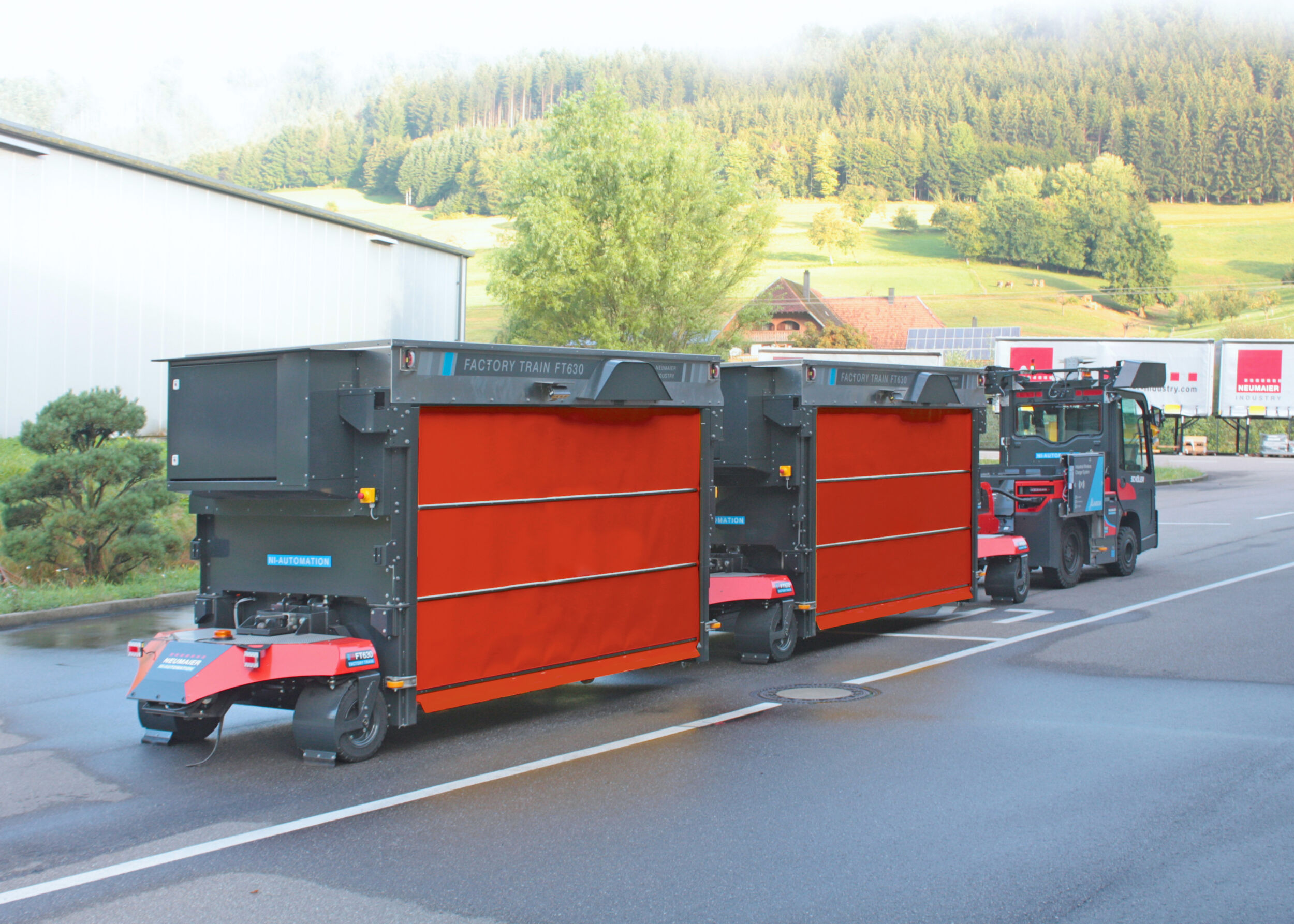 Vollautomatisierter und autonomer Outdoor-Routenzug Factory Train FT630 von Neumaier Industry mit Teleskopgabel-Warenträger für die automatisierte Aufnahme und Abgabe von Ladungsträgern auf/von Übergabestationen oder direkt auf den bzw. vom Boden.