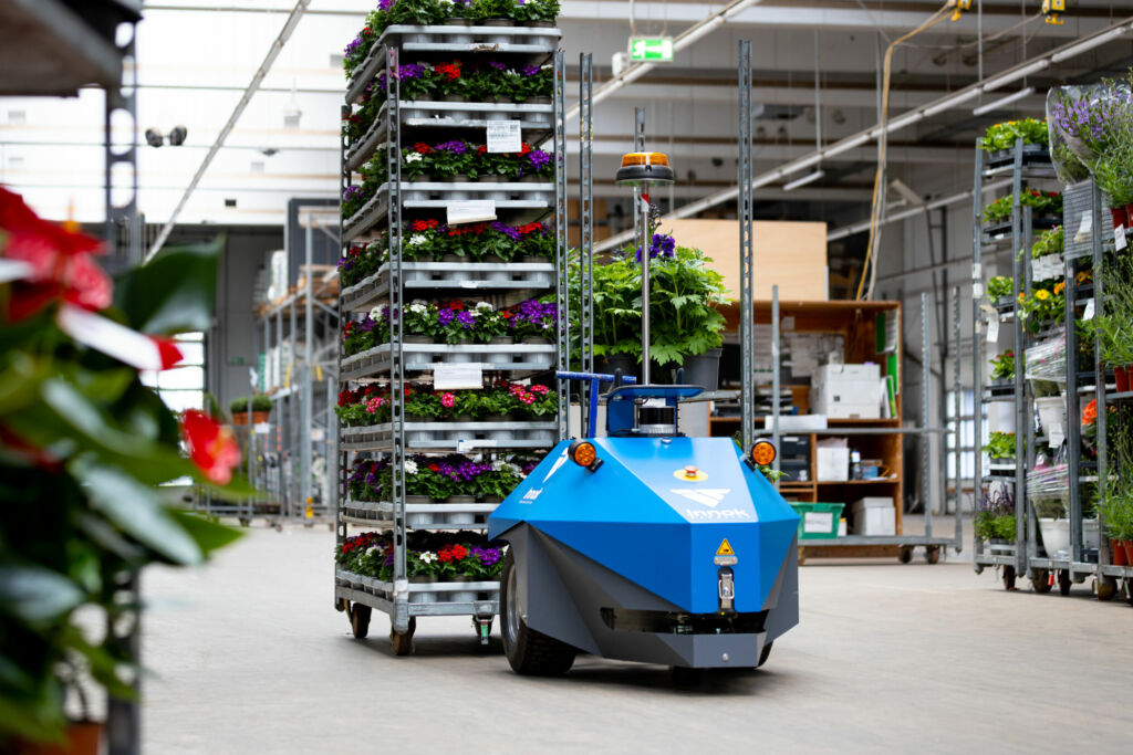 Vom Outdoor-Wareneingang ins Indoor-Lager und zurück 1 Der Multiterrain-AMR Induros transportiert Anhänger mit Pflanzen vom Indoor- in den Outdoor-Bereich und wieder zurück.