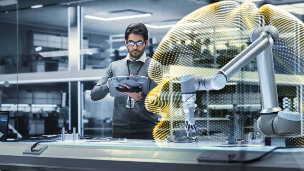 Schutzzaunlose Sicherheitszonen 1 Robotics Engineer Researching and Developing a Technological Robot Arm Project, Standing with Tablet Computer in Scientific Technology Lab. Young Male Working on an AI Robotic Arm.; Shutterstock ID 2227917411; purchase_order: -; job: -; client: -; other: -