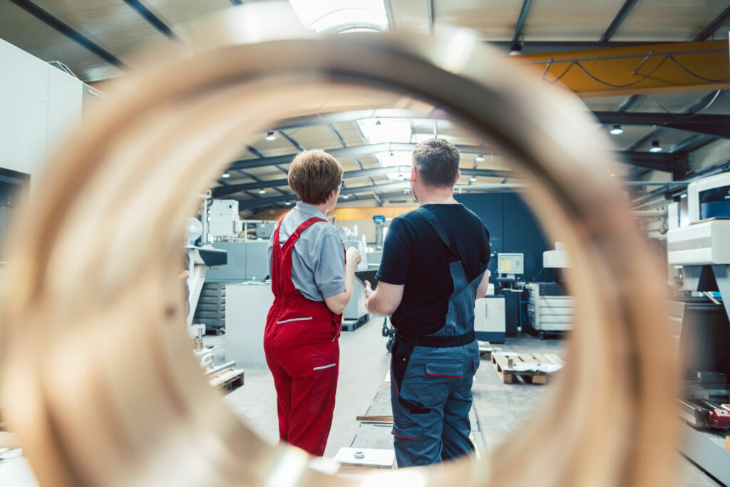 Ifo-Geschäftsklimaindex fällt um 1,3 Punkte 1 Workers standing on the factory floor seen through a workpiece