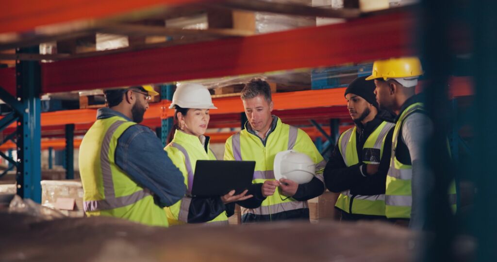 Die Intralogistik und das Workforce Management 1 Employees tablet and group in warehouse teamwork and inventory with connection. People factory and supervisor with tech cooperation and conversation with communication planning and logistics