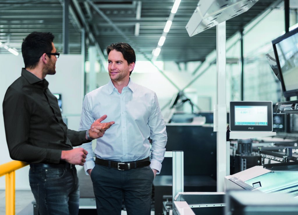 Pilz informiert zum Cyber Resilience Act 1 Two businessmen talking in modern factory