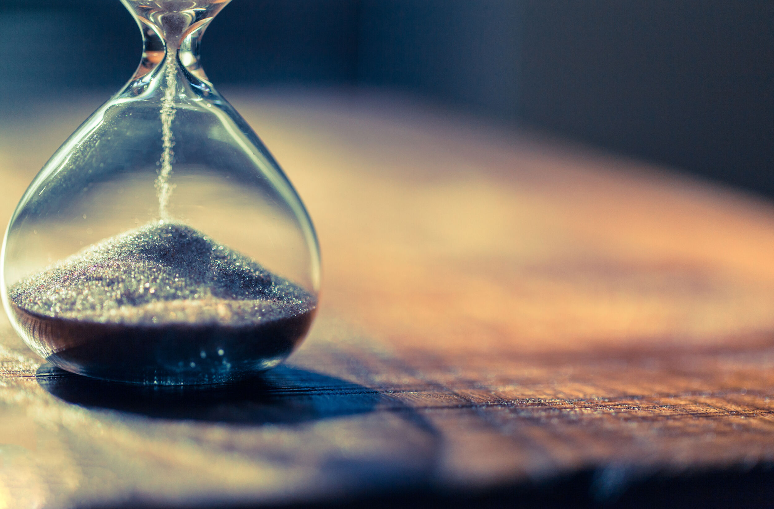 Sand running through the bulbs of an hourglass measuring the passing time in a countdown to a deadline with copy space