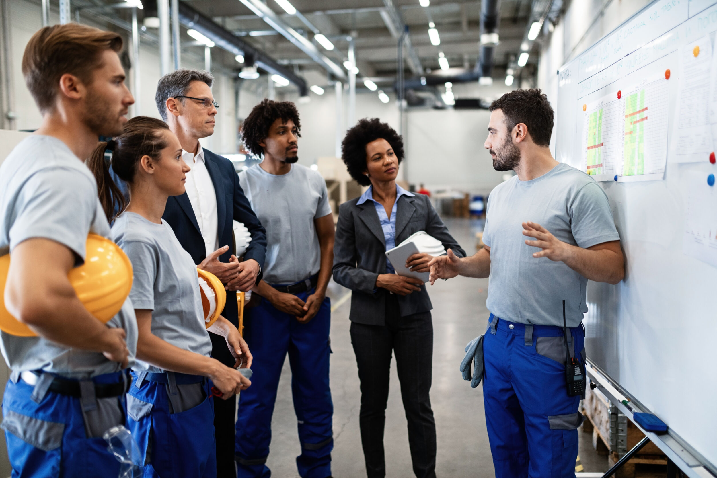 Young worker giving presentation in front of whiteboard in a factory