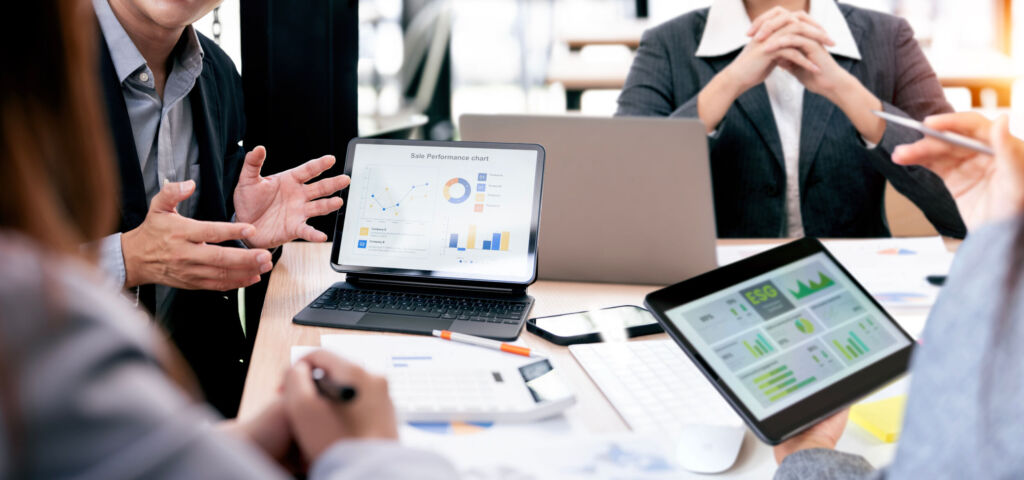 Warum Compliance- und Nachhaltigkeitsdaten in Beschaffung und Produktion zusammengehören 1 Business team analyzing financial sales performance charts and ESG reports on digital tablets and laptop during a collaborative meeting in the office