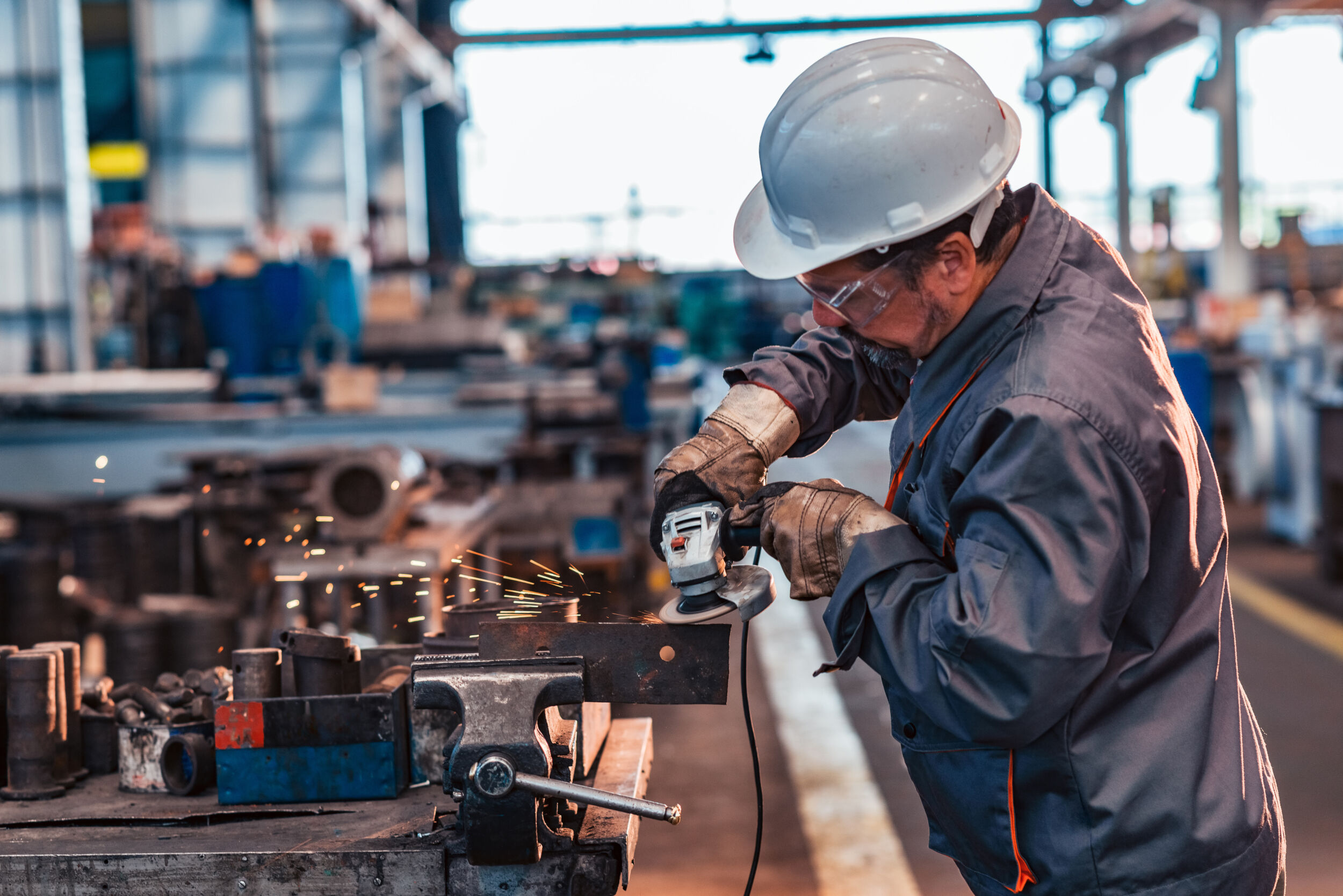 Unternehmen melden Stimmungsaufhellung 12 Skilled industrial worker grinding metal part