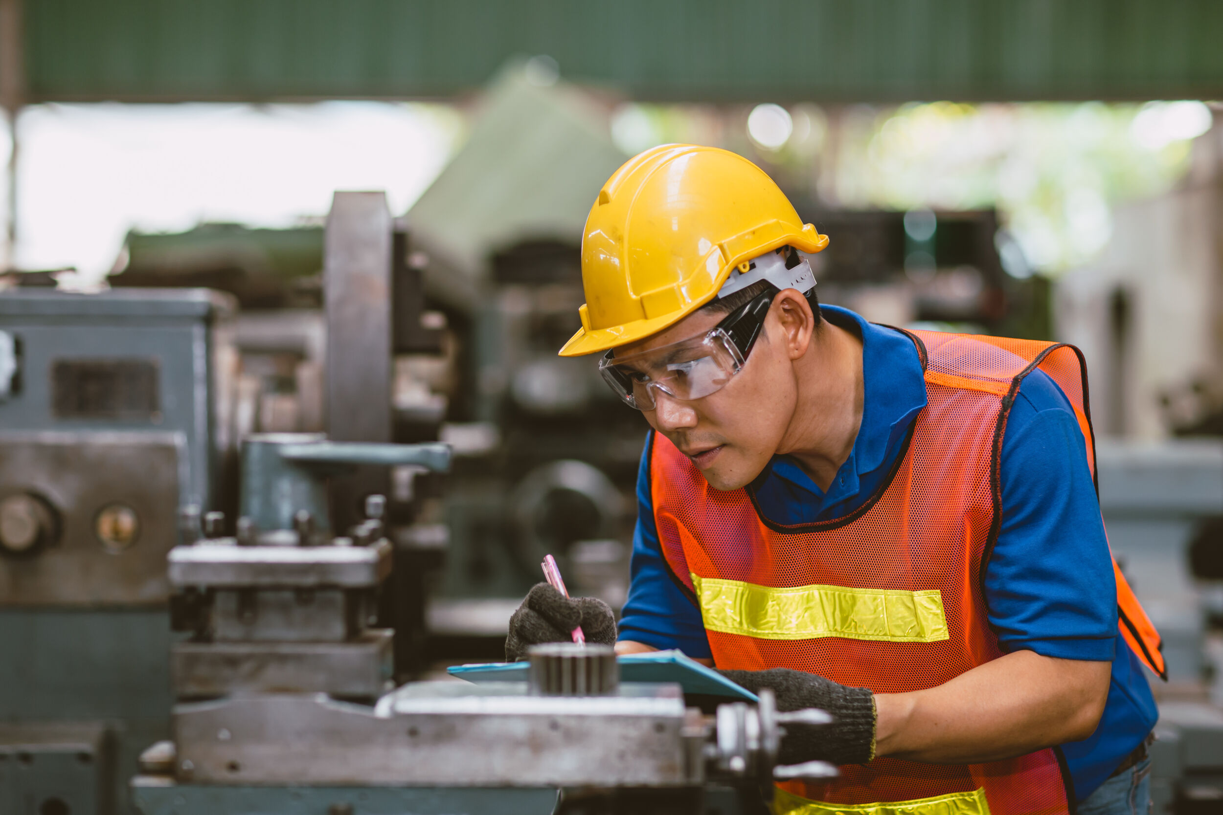 Asian expert technician engineer male focus detail working precision manual cut lathe milling metal production in heavy industry