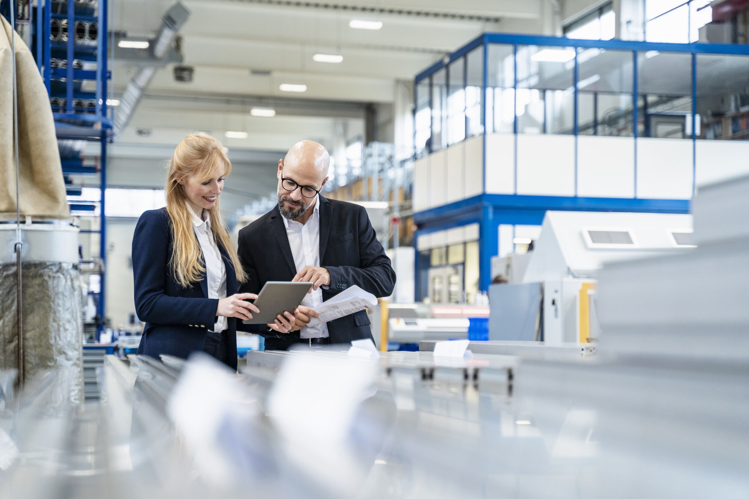 Businessman and businesswoman with tablet discussing in factory