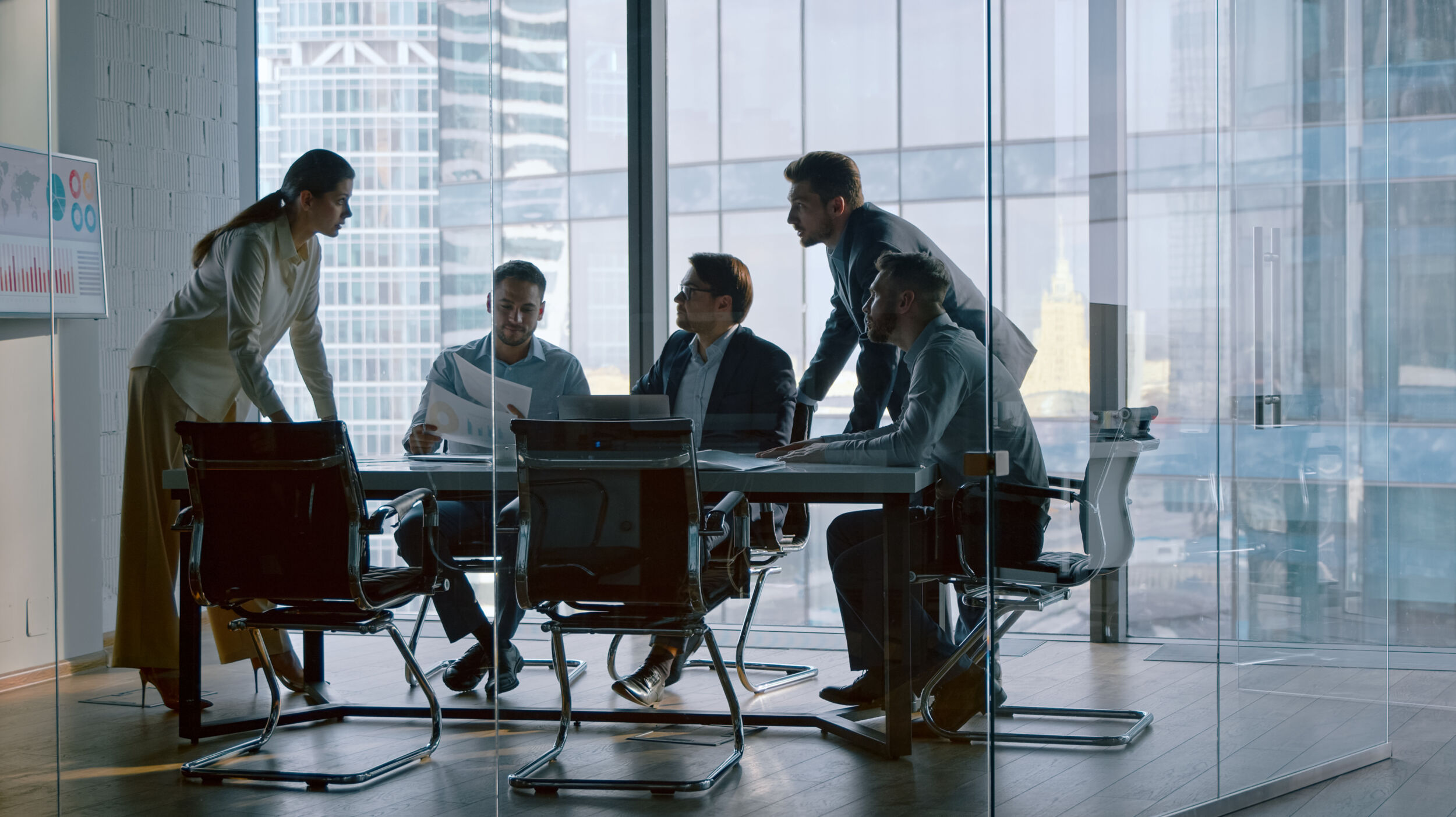 Chief corporate manager talking with team at desk in meeting room