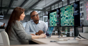 Young Engineer And Developer Collaborate On Electronic PCB Design At Office