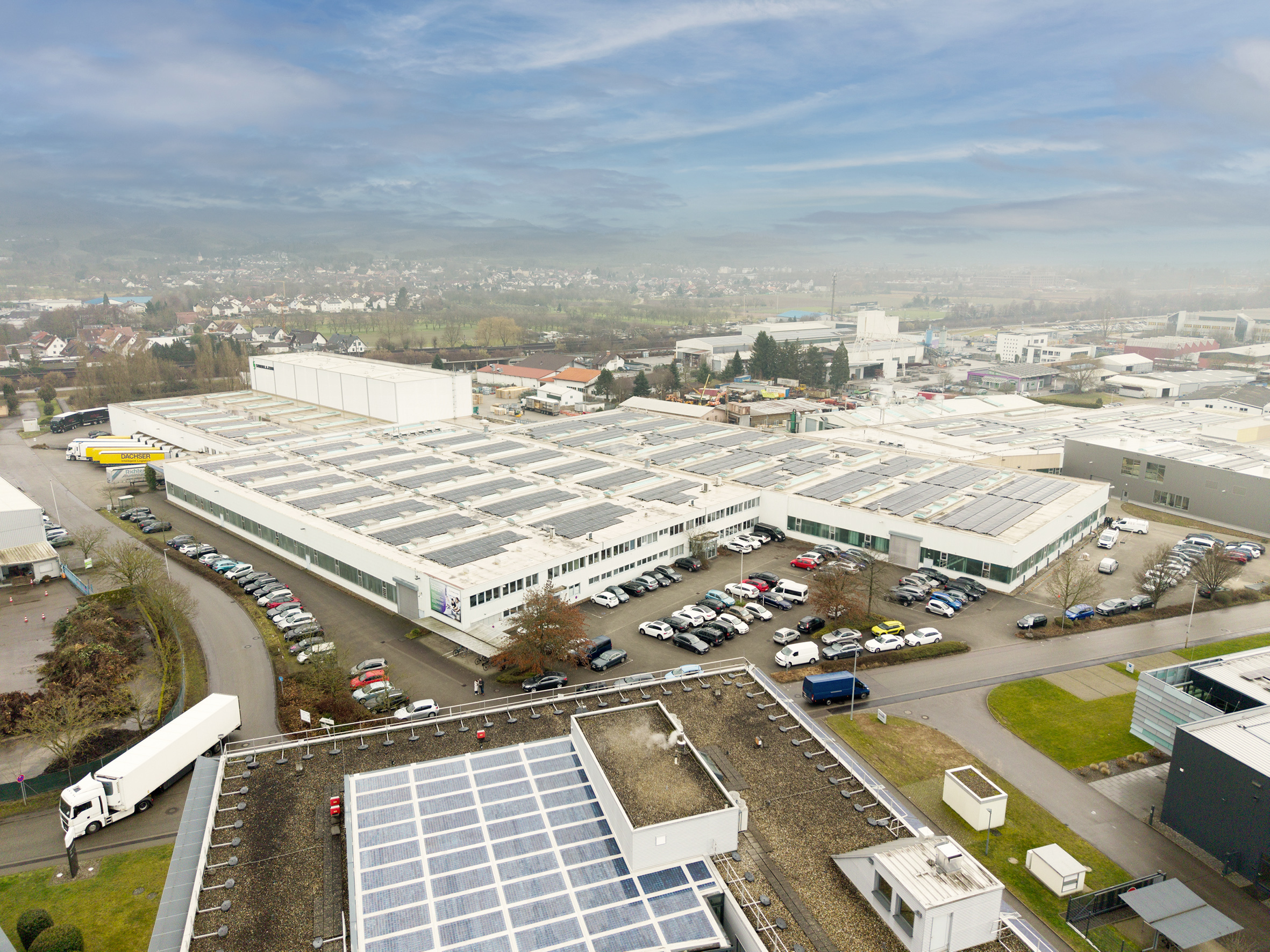 Die rund 3.410 PV-Module auf dem Bürogebäude (im Vordergrund) und den Werkhallen erzeugen jährlich etwa 1.500 Megawattstunden grünen Strom. Davon profitiert auch der Einsatz des E-Trucks in Kooperation mit dem Dachser Logistikzentrum Karlsruhe.