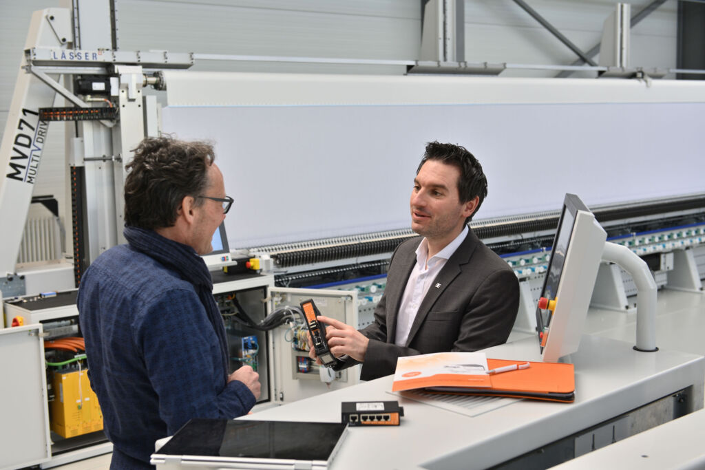 So nutzt Stickmaschinenhersteller Lässer einen cloudbasierten Fernzugriff U-Link 1 Vor der Stickmaschine MVD71 erklärt Peter Hirt, Segment Manager Machinery & Automation Sales bei Weidmüller dem Softwareentwickler und Projektverantwortlichen bei Lässer, Patrik Schwarz, die Vorteile des Industrial-Security-Routers von Weidmüller.
