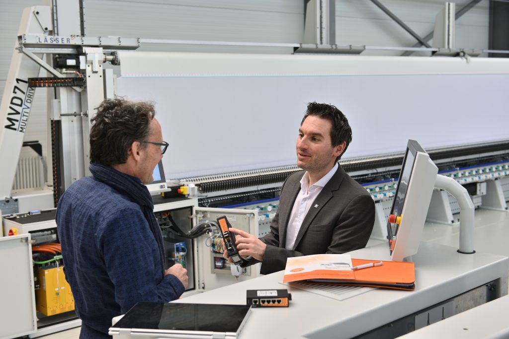 So nutzt Stickmaschinenhersteller Lässer einen cloudbasierten Fernzugriff U-Link 1 Vor der Stickmaschine MVD71 erklärt Peter Hirt, Segment Manager Machinery & Automation Sales bei Weidmüller dem Softwareentwickler und Projektverantwortlichen bei Lässer, Patrik Schwarz, die Vorteile des Industrial-Security-Routers von Weidmüller.