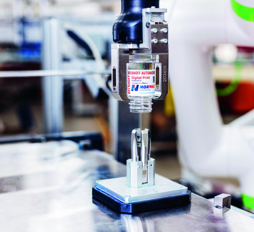 Digitaldruck in sechs Freiheitsgraden 2 Nach Abschluss des Druckvorgangs nimmt ein Roboter die Behälter aus den Produkthalterungen der magnetisch schwebenden Mover.