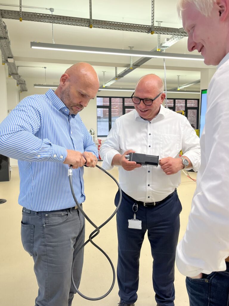 Reallabor statt Showroom 4 Frank Nolte (links) testet im Beisein von Geschäftsführer Dr. Ulrich Viethen, und Christian Knoop (rechts) das Schnellanschlusssystem der MQ15 Power-Steckverbinder, die Murrelektronik für die Energieversorgung von Asynchron- und Drehstrommotoren bis 7,5kW sowie Frequenzumrichter entwickelt hat.