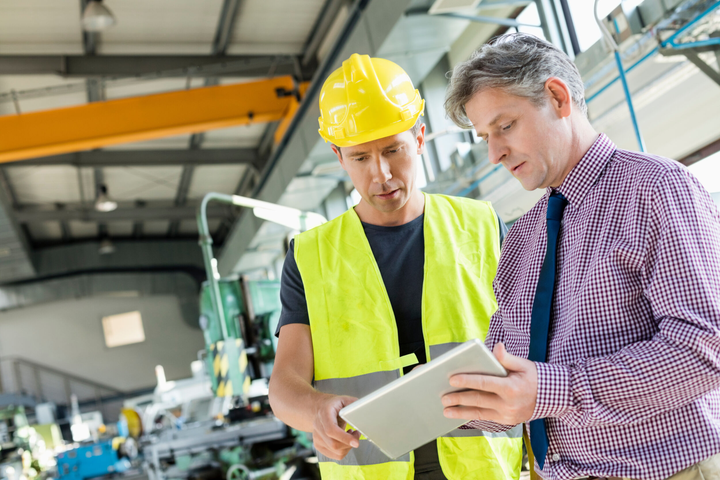 Supervisor and manual worker using digital tablet in metal industry