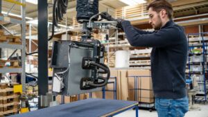 Ergonomische Palettierung: Der Heavylift 80kg mit einem Seiten- lifter hebt den Gebläsekonvektor vom Prüftisch und ermöglicht das sichere Umsetzen auf Palette oder Rollenbahn.