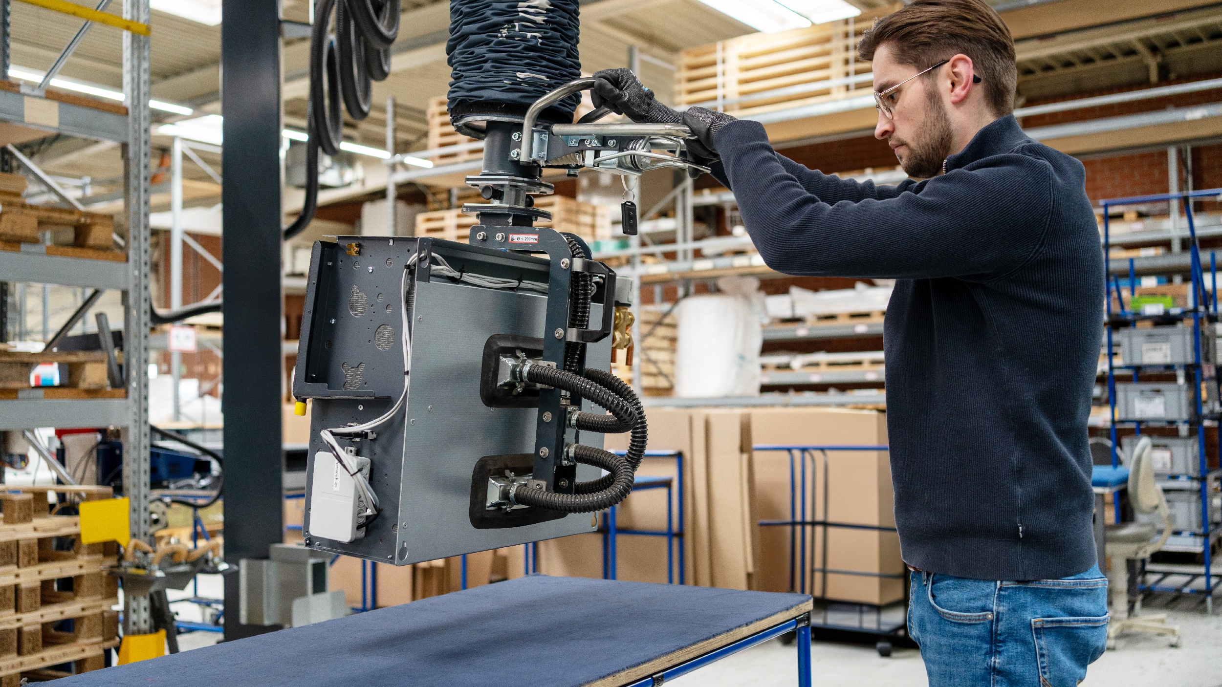 Ergonomische Palettierung: Der Heavylift 80kg mit einem Seiten- lifter hebt den Gebläsekonvektor vom Prüftisch und ermöglicht das sichere Umsetzen auf Palette oder Rollenbahn.